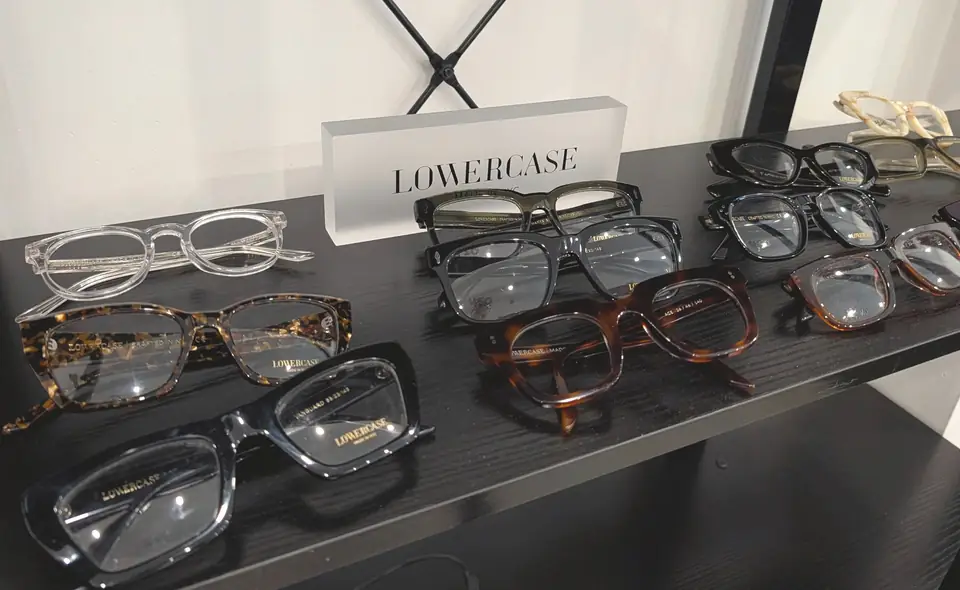 A selection of actual Lowercase eyeglass frames on a black display shelf at Park Slope Eye