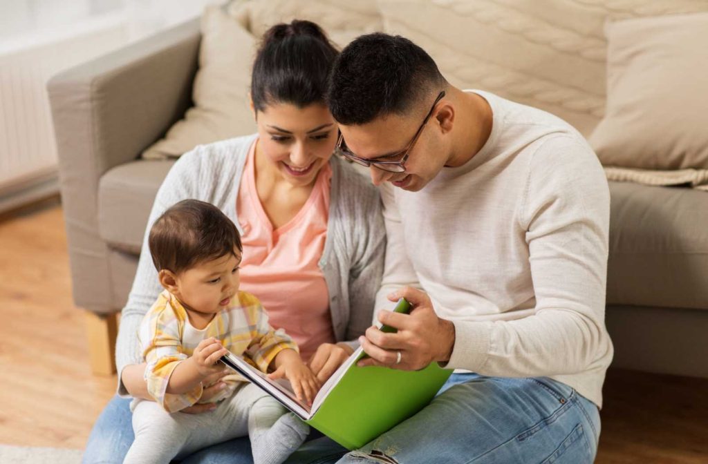 family gathered around book while baby touches pages in the warm lighting of a livingroom