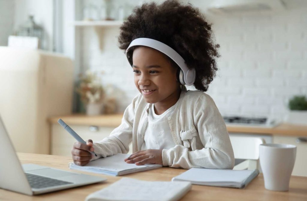 Child in white background and clothing happily learning over computer