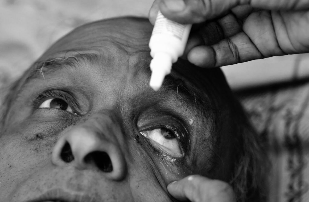 Eyedrops being administered to older man to dilate his eyes