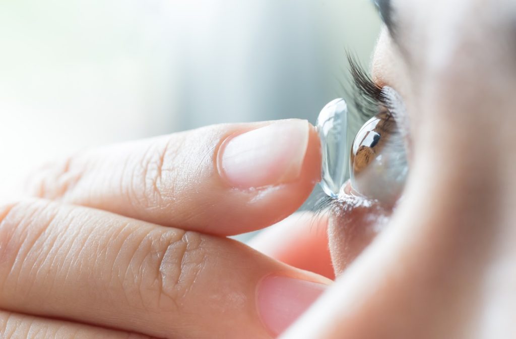 A woman putting in soft contact lenses to help correct her vision due to astigmatism