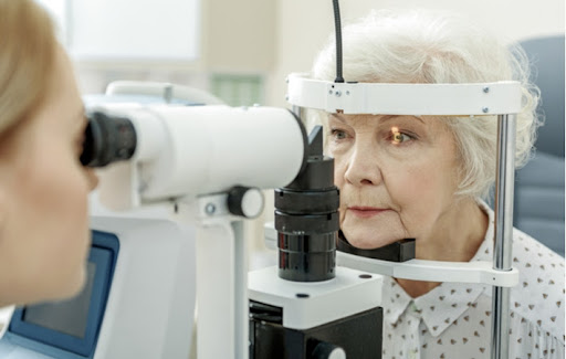 An optometrist giving an elderly woman an eye exam to protect her vision against conditions like glaucoma and tunnel vision