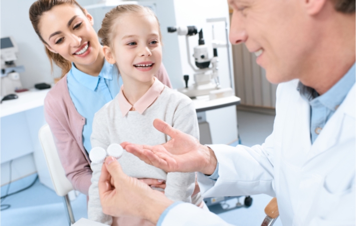 A male optometrist preparing to administer contact lenses to a young girl to help control her myopia