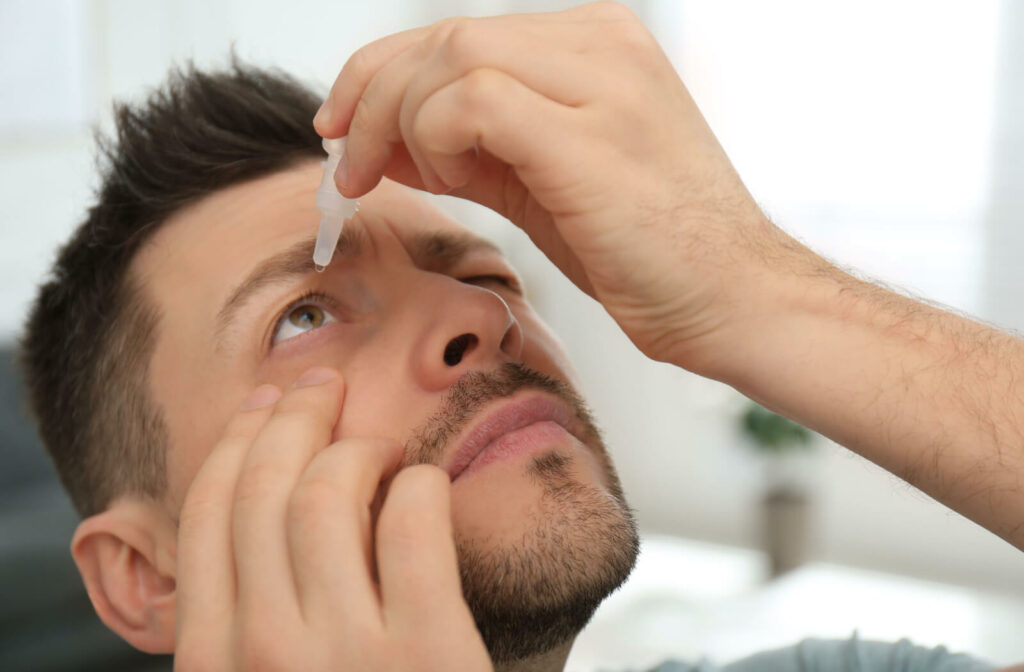 A man is using lubricating eye drops to treat his dry eyes.