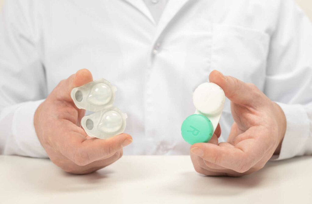 An eye doctor holding a contact lens blister pack in one hand and a contact lens case in the other hand.
