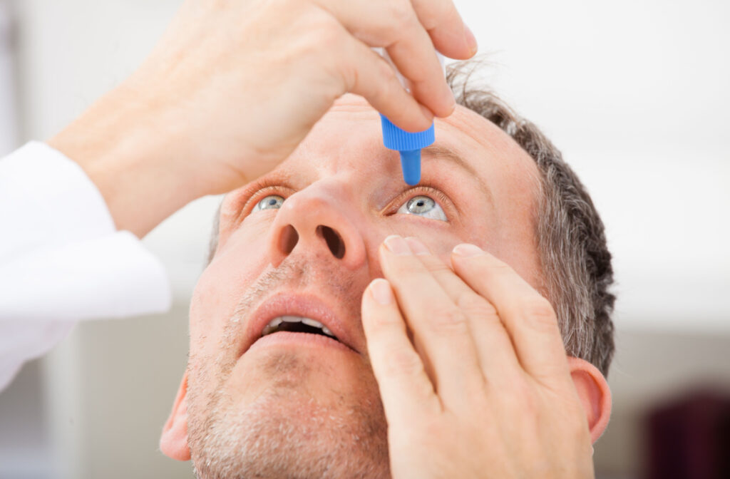 A man applying eye drops on his left eye.