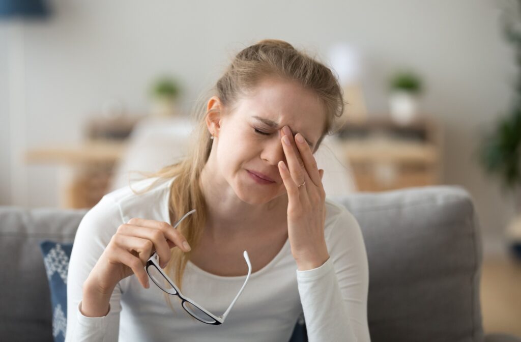A young woman closes her eyes tightly from severe eye discomfort.