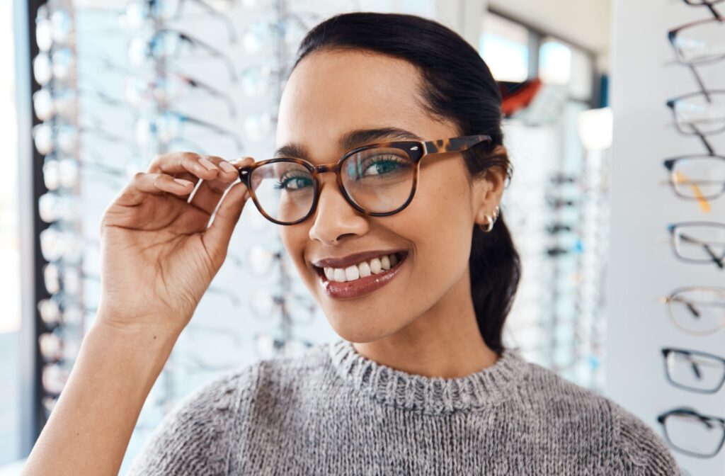 A patient smiling and putting on their prescription glasses to support their eye health and visual development.